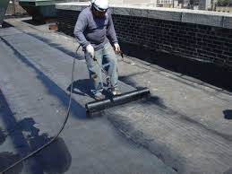 Roofer rolling a flat roof membrane